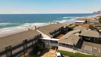 Oceanfront hotel complex with a view of the blue sea and sandy beach under a clear sky.